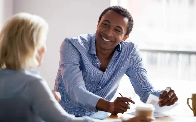 Imagem de um homem e uma mulher fazendo uma reunião one-on-one, ambos sorrindo